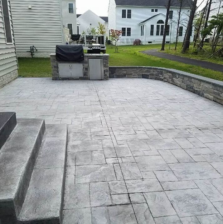 A backyard concrete patio with brick overlay